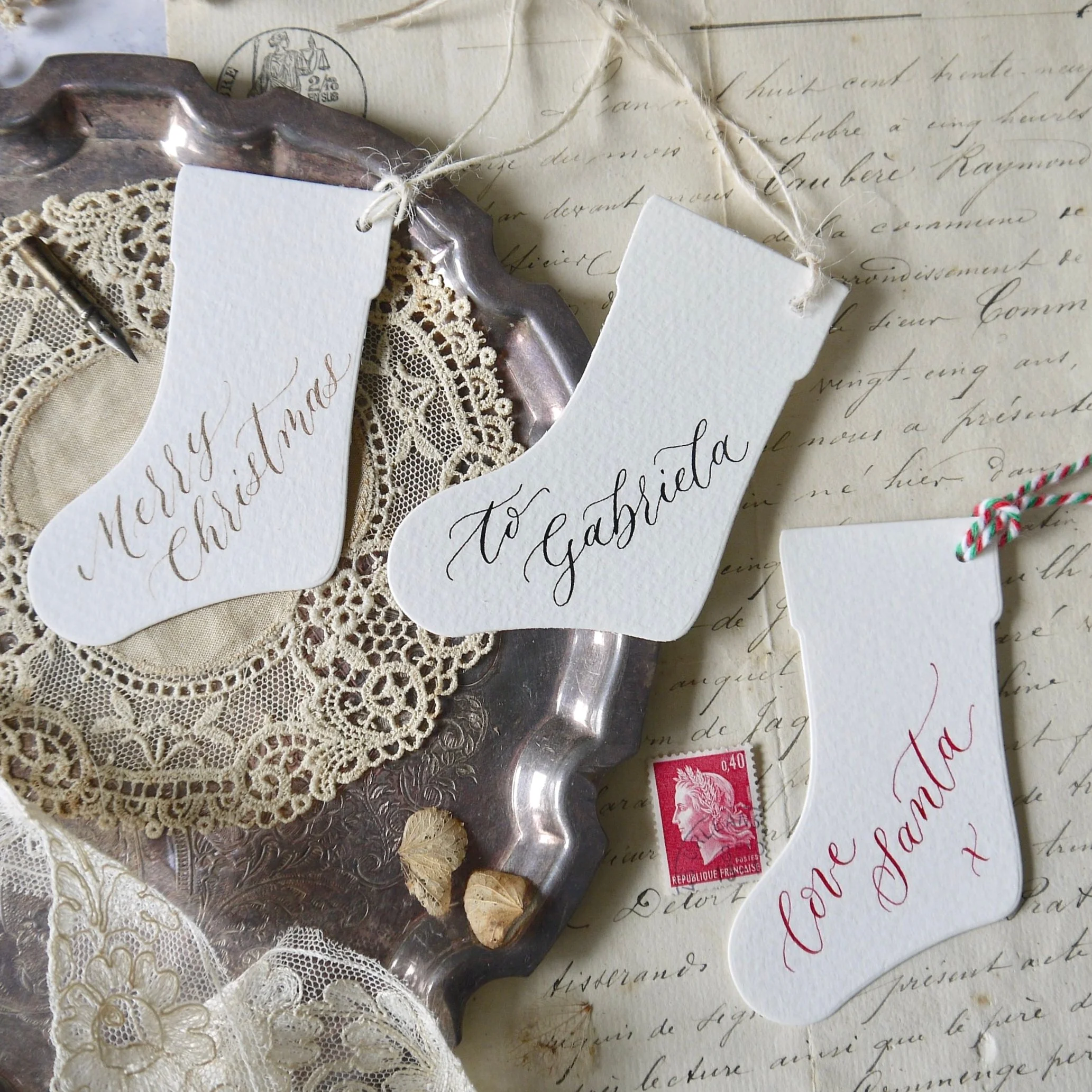 Set of handcrafted calligraphy gift tags with twine, arranged on a tabletop