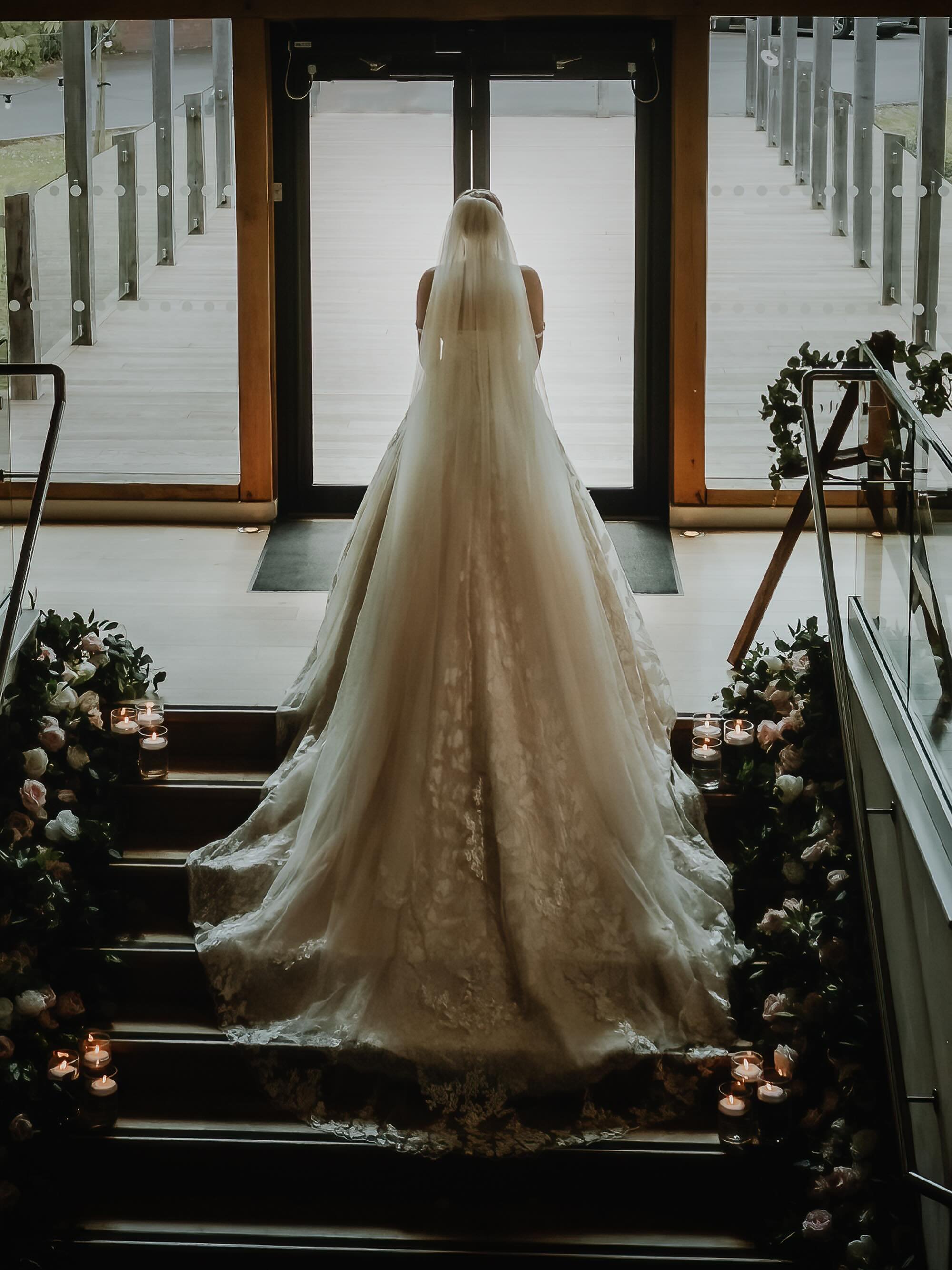 There&rsquo;s a quiet kind of elegance in moments like this.  A bride, her veil spilling softly down the steps @themillbarnsvenue , pausing just long enough for the dress, the light, and the atmosphere to settle into place.

I photograph weddings in 