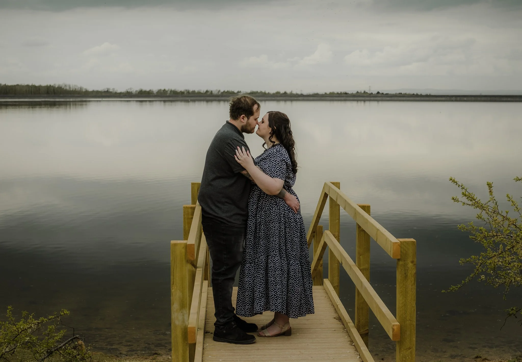 Leah and Josh on a bridge at Foremark Reservoir during their relaxed engagement photoshoot in Derbyshire
