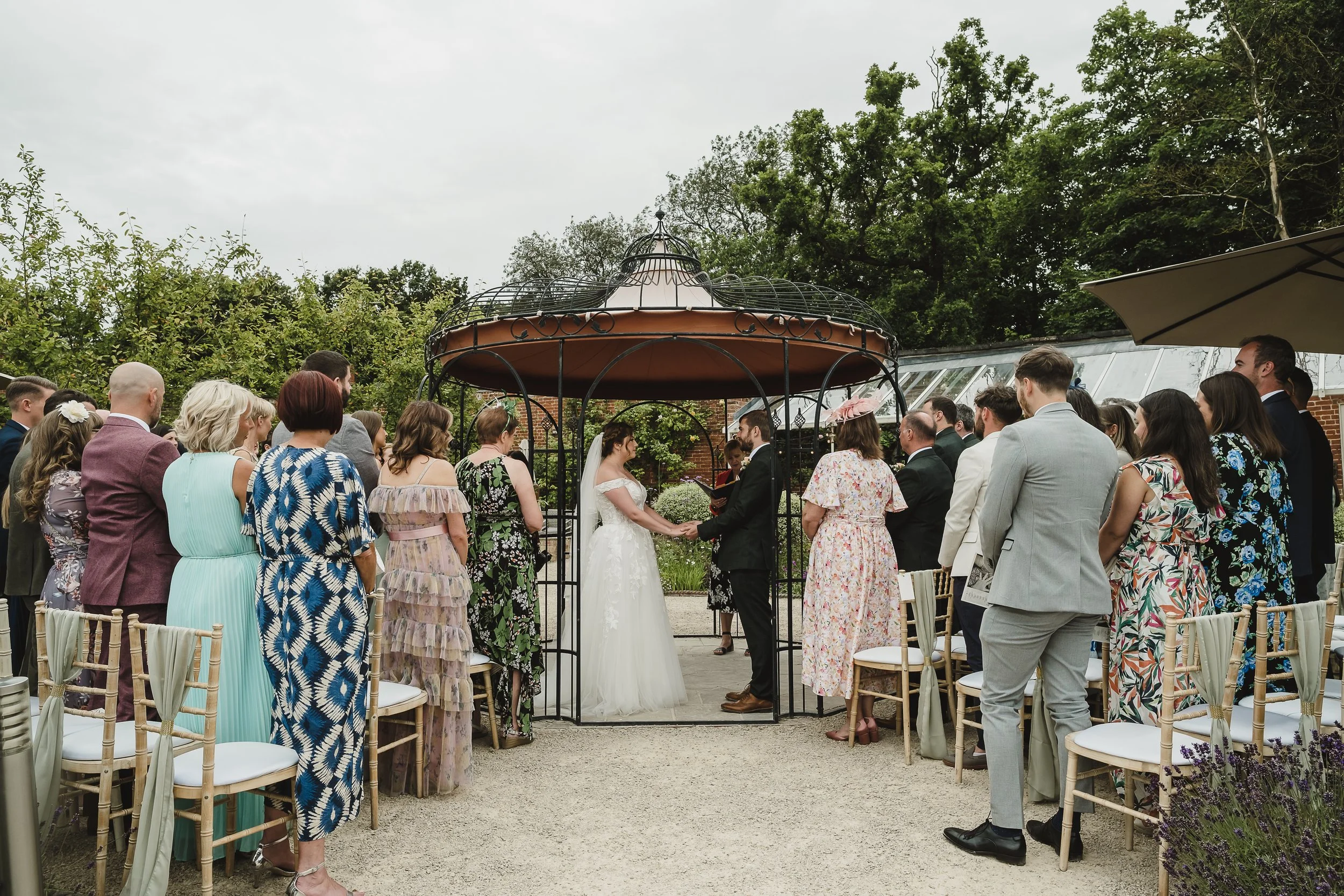 Bride and groom exchanging vows in an outdoor ceremony at The Walled Garden, Besston Fields