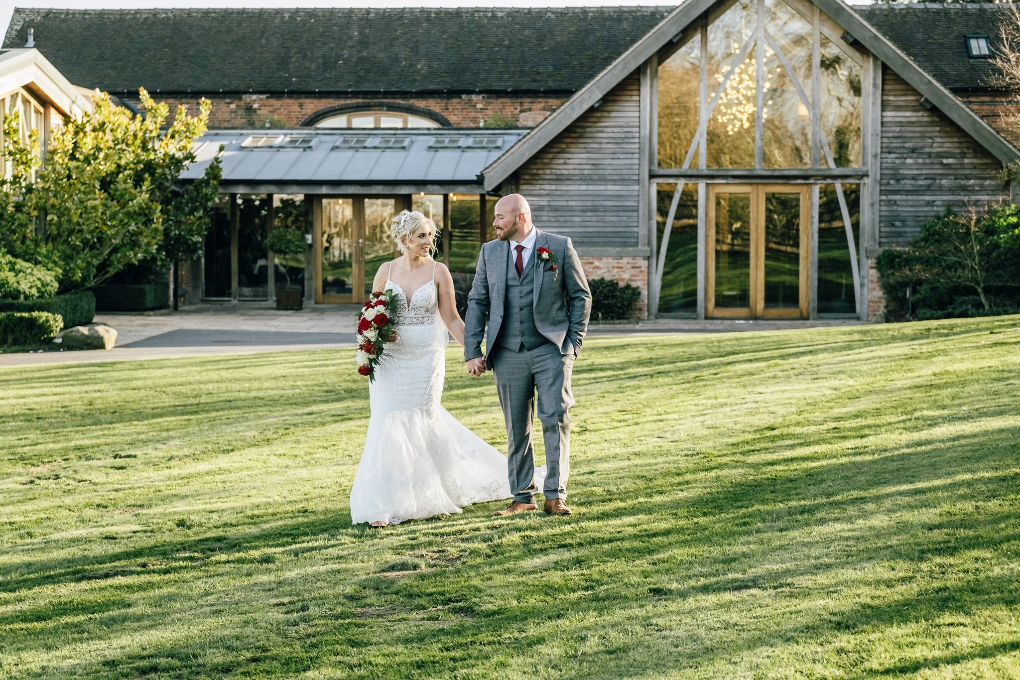 bride and groom walking with Mythe Barn in the background