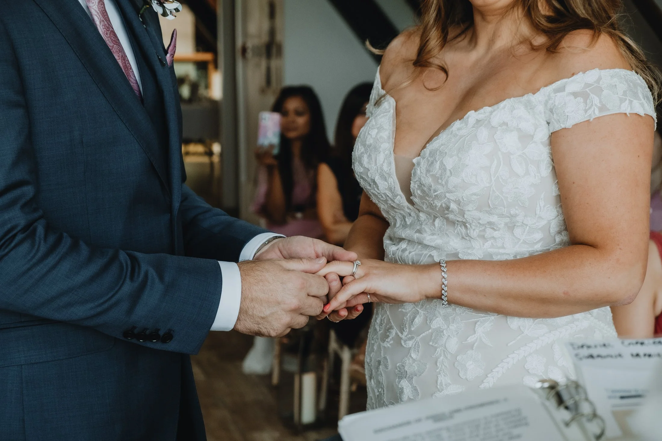 groom putting a wedding ring on the bride's finger in intimate ceremony in Northampton