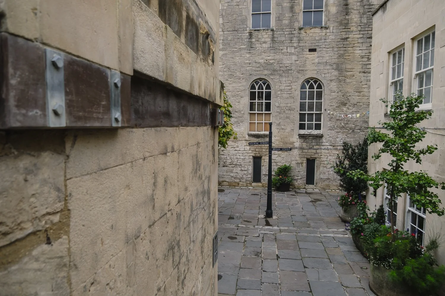 A historic cobbled street in Bath lined with beautiful honey-coloured stone buildings.