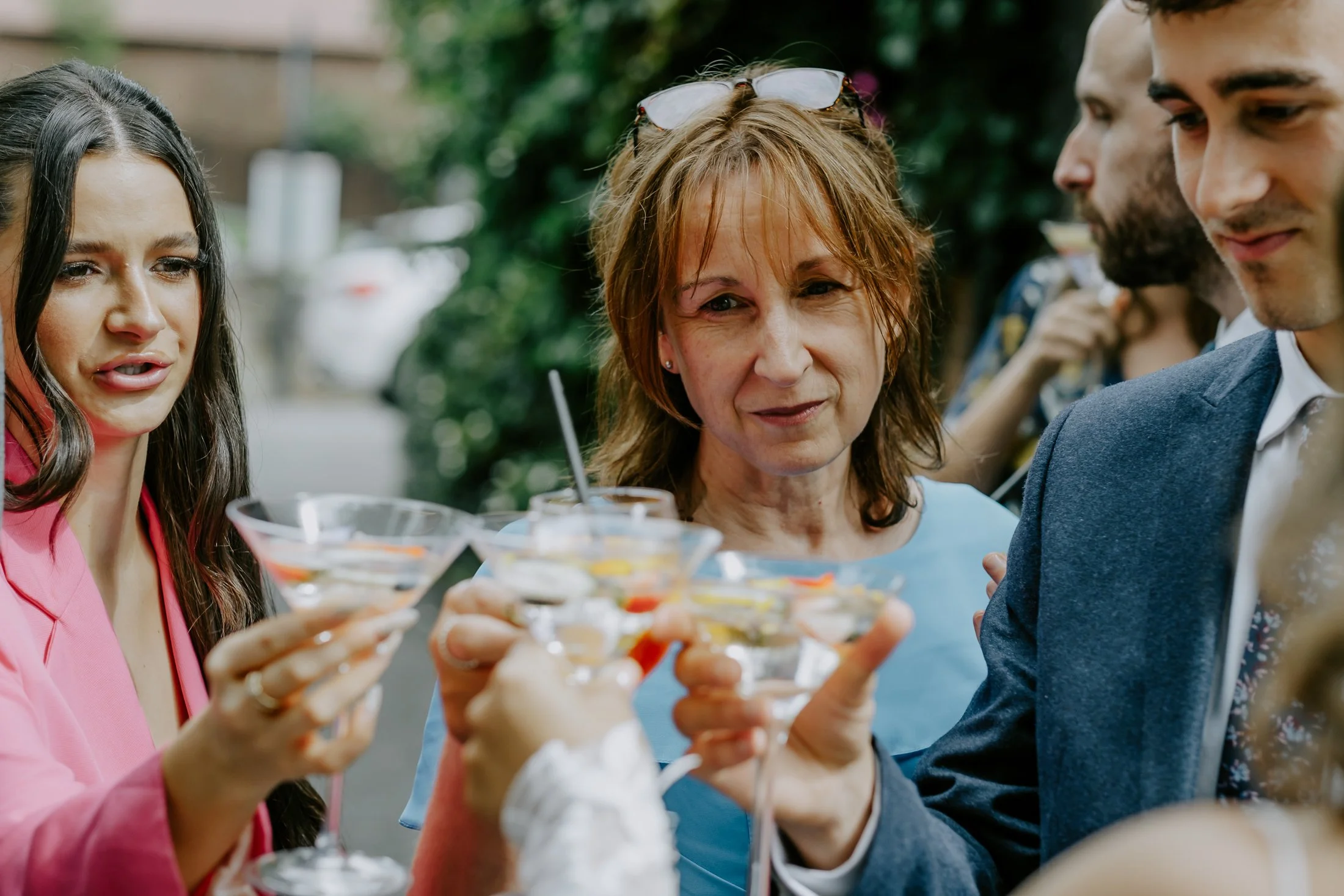 Group of people at an outdoor gathering raising their cocktails for a toast.