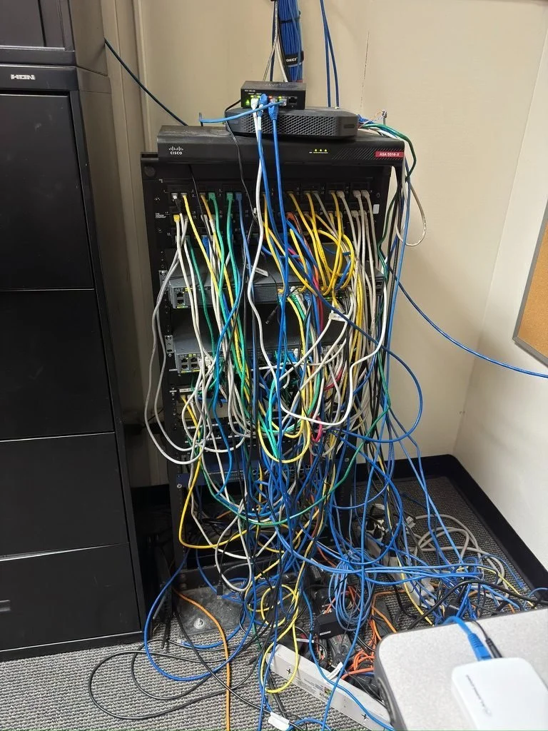 Network rack before cleanup, with tangled patch cables piled on the floor