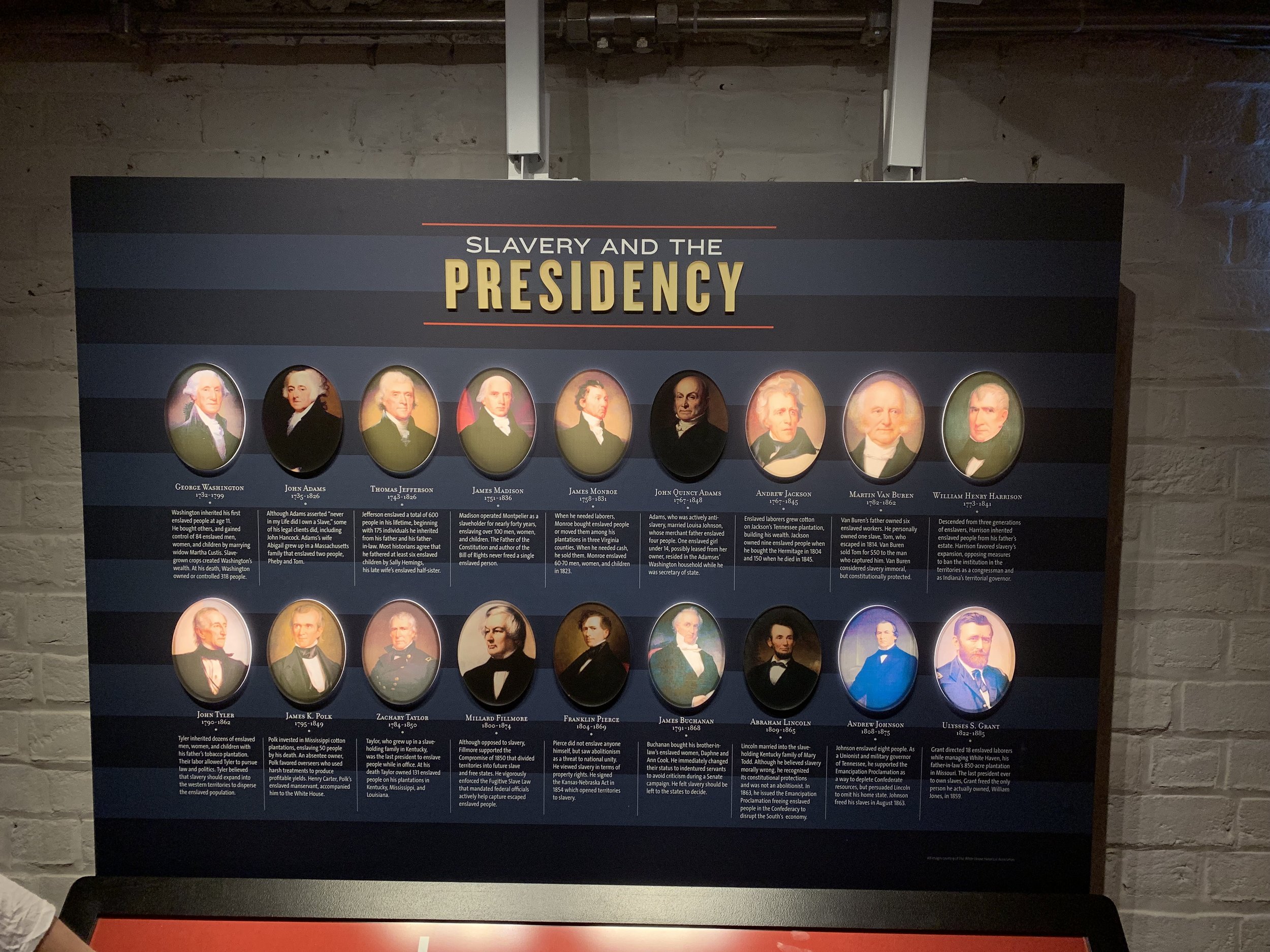 Thirteen of the first eighteen presidents were slave holders. The backlit portraits indicate slave owning presidents. This graphic is from “The Mere Distinction of Colour” exhibition in the cellar of the Montpelier. Created by Proun Design , The Montpelier Foundation. Photo by Renée Ater, August 2019.