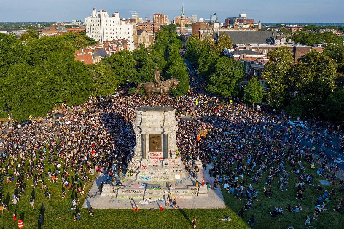 A large group of protesters gather around the statue of Confederate General Robert E. Lee on Monument Avenue near downtown in Richmond, Va.