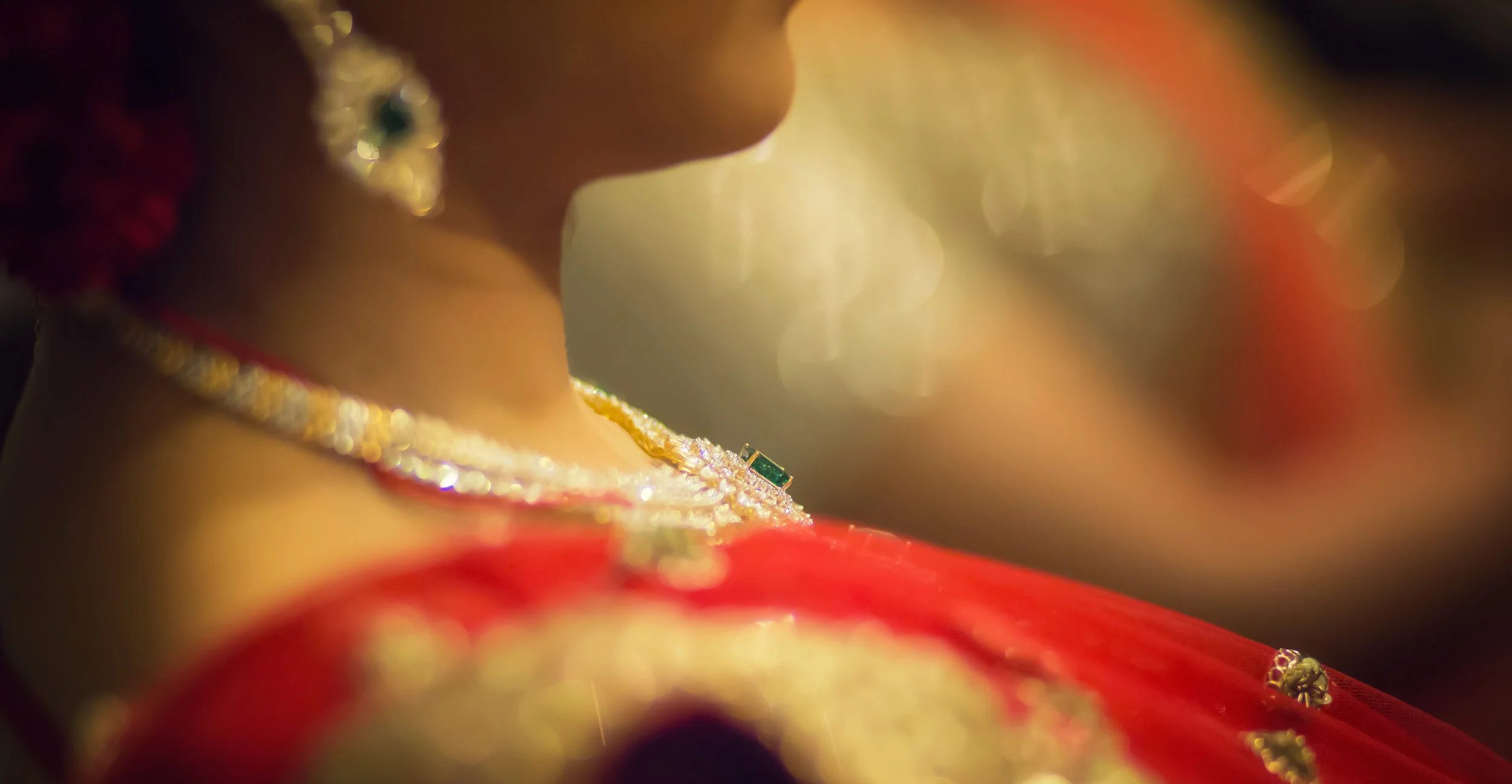 Close-up of a woman wearing traditional Indian attire and jewelry, focusing on her neck and shoulders with blurred background.