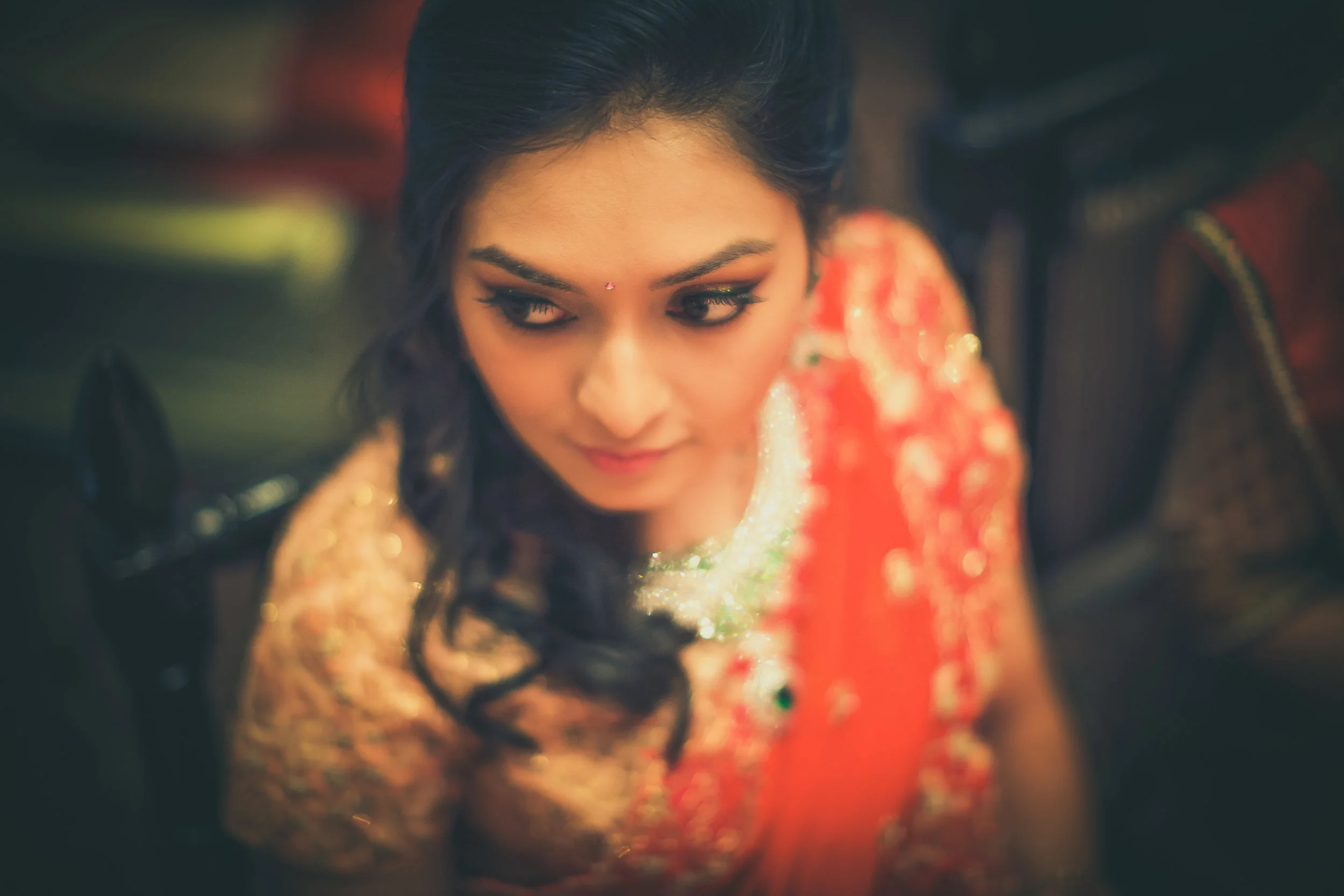 A woman dressed in traditional Indian attire, with dark hair and eye makeup, looking over her shoulder.
