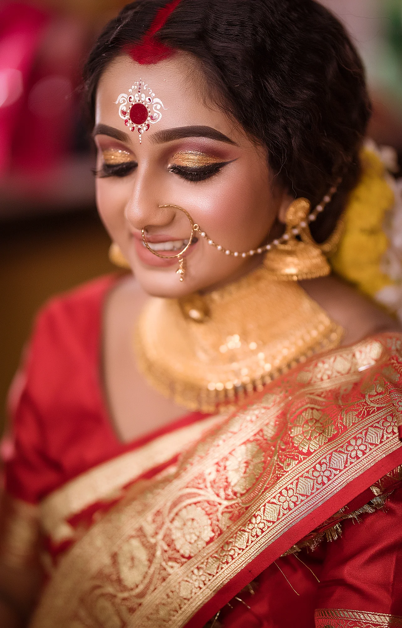 A woman dressed in traditional Indian attire with intricate jewelry, makeup, and a decorative bindi on her forehead.