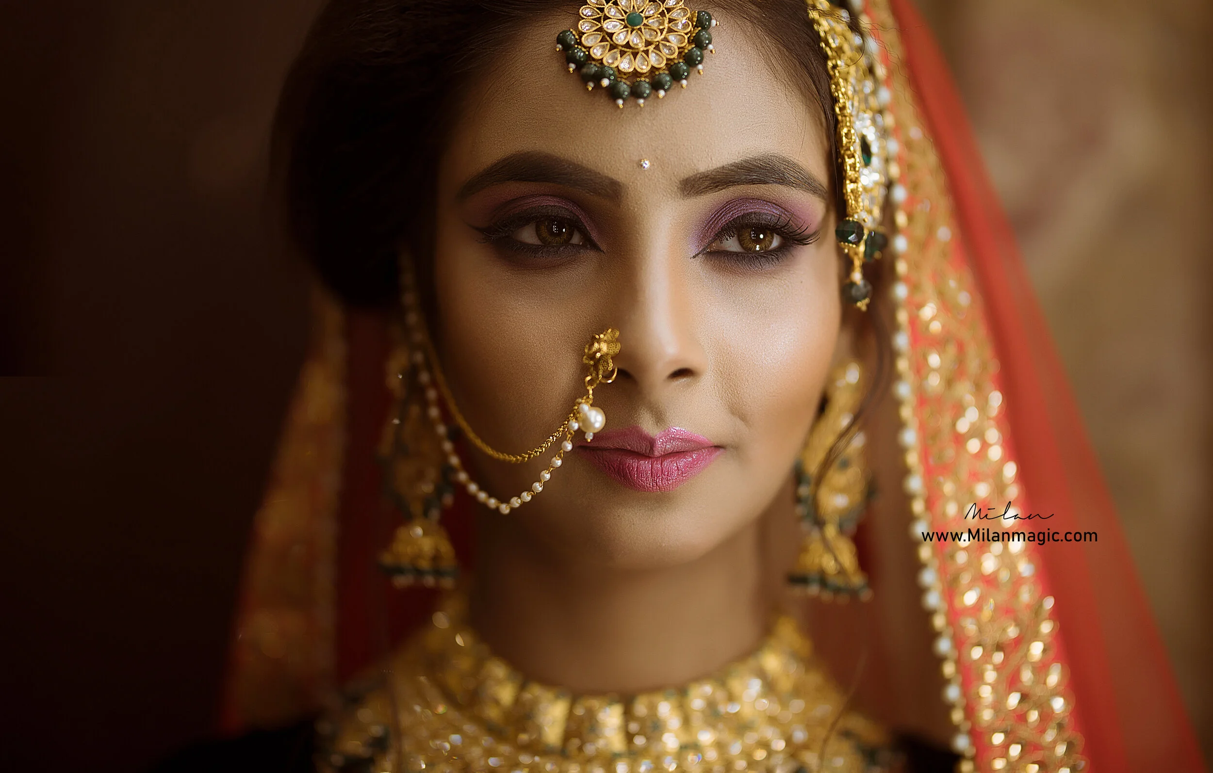 Close-up of an Indian bride wearing traditional gold jewelry and a red and gold bridal saree or lehenga, with intricate makeup and a detailed headpiece.