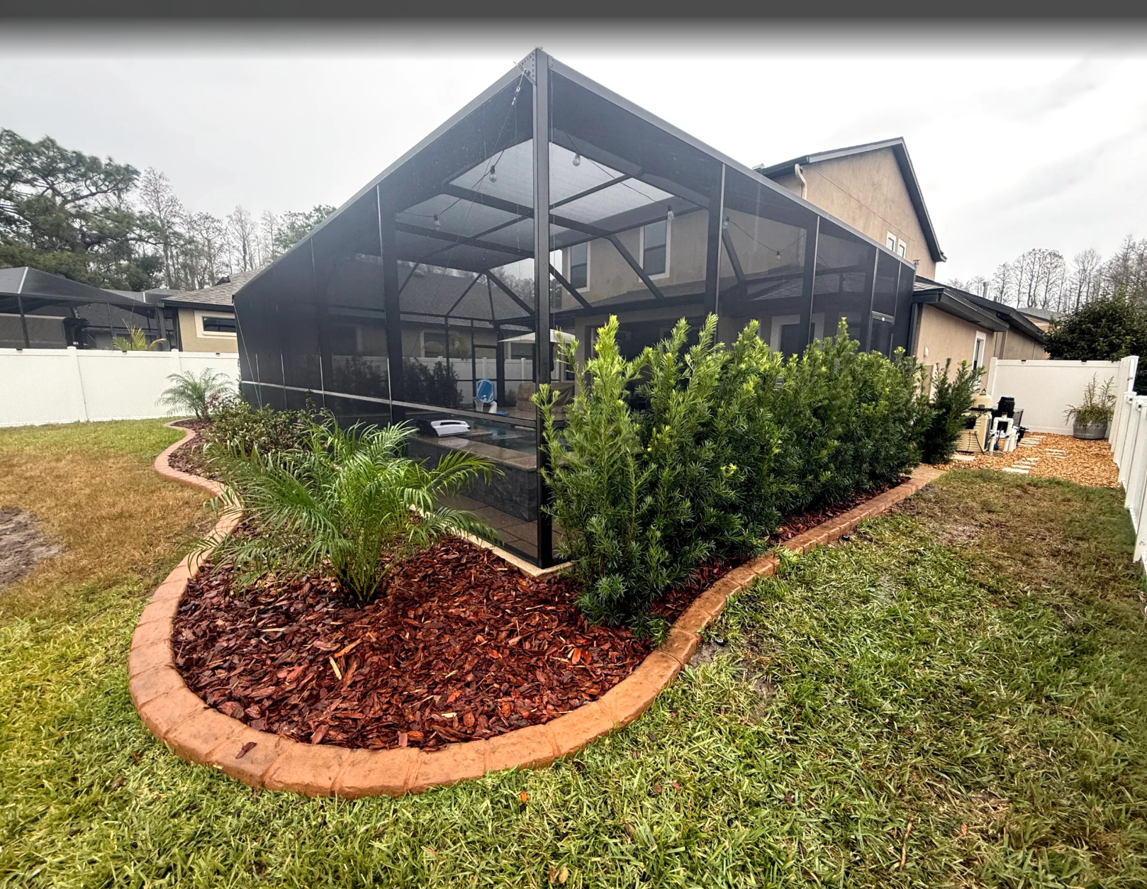 rlc-privacy-shrubs-and-small-palms-in-a-curved-mulch.webp