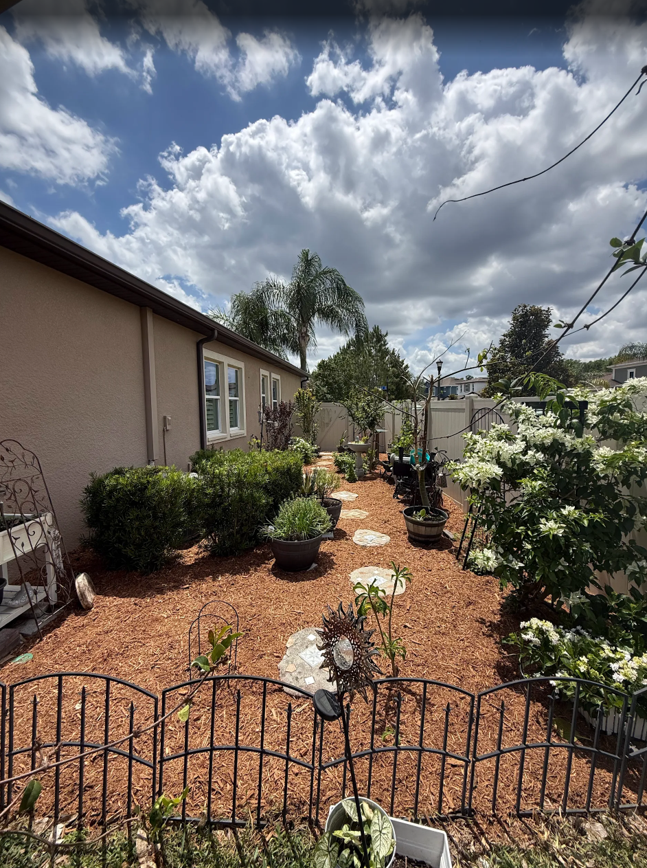 rlc-mulched-garden-beside-a-home-with-shrubs-potted-plants.webp