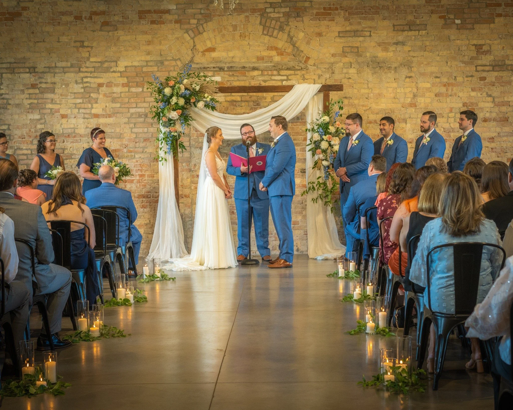 Wedding ceremony at a Chicago indoor venue with professional DJ and sound setup, bride and groom exchanging vows under floral arch