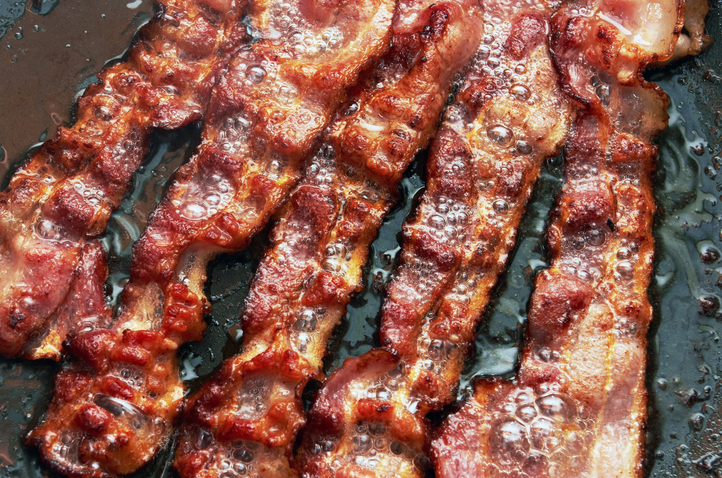 Bacon-slice-being-cooked-in-frying-pan-509662147_4000x2653.jpeg
