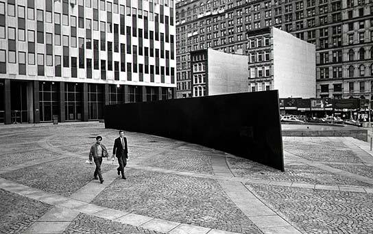 Richard Serra “Titled Arc” / US government
(In 1981, the US Arts-in-Architecture program (part of the US General Services Administration) commissioned artist Richard Serra to create a work of public art for the Federal Plaza in NYC.
The work proved controversial from the outset: some balked at its cost ($175,000 for a solid block of steel); others objected to the graffiti and rats it seemed to attract; others simply found it an eyesore. Most significantly, a number of people working in surrounding buildings complained that the work was an inconvenience, as they were forced to walk around the massive sculpture as they crossed the plaza. (Which, according to Serra, was precisely the point: “The viewer becomes aware of himself and of his movement through the plaza. As he moves, the sculpture changes. Contraction and expansion of the sculpture result from the viewer’s movement. Step by step the perception not only of the sculpture but of the entire environment changes.”)
As a result of this controversy, Judge Edward Re began a campaign to have the the sculpture removed. In 1985, there was a public hearing to determine whether Tilted Arc should be relocated. Serra, for his part, argued that work was site specific, that to remove it would be to destroy it, and if it was relocated, he would remove his name from the piece. At the end of the hearing, a jury ruled 4-1 to remove the piece. Serra appealed, and the ruling was debated over the course of the next five years or so.
In the end, the jury’s ruling was upheld. Exercising proprietary rights, authorities of the General Services Administration ordered the destruction of the public sculpture that their own agency had commissioned ten years earlier. Government workers dismantled the work on March 15, 1989.)
