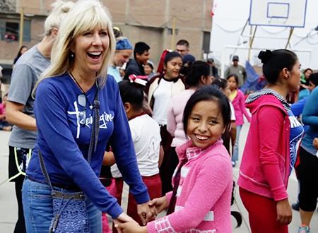 Linda dances with one of the children as the team plays music for the community.