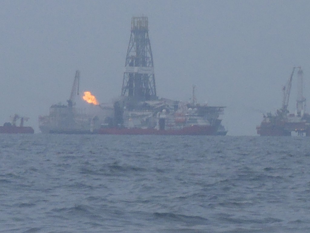 Drill ship with flare through the rain.
