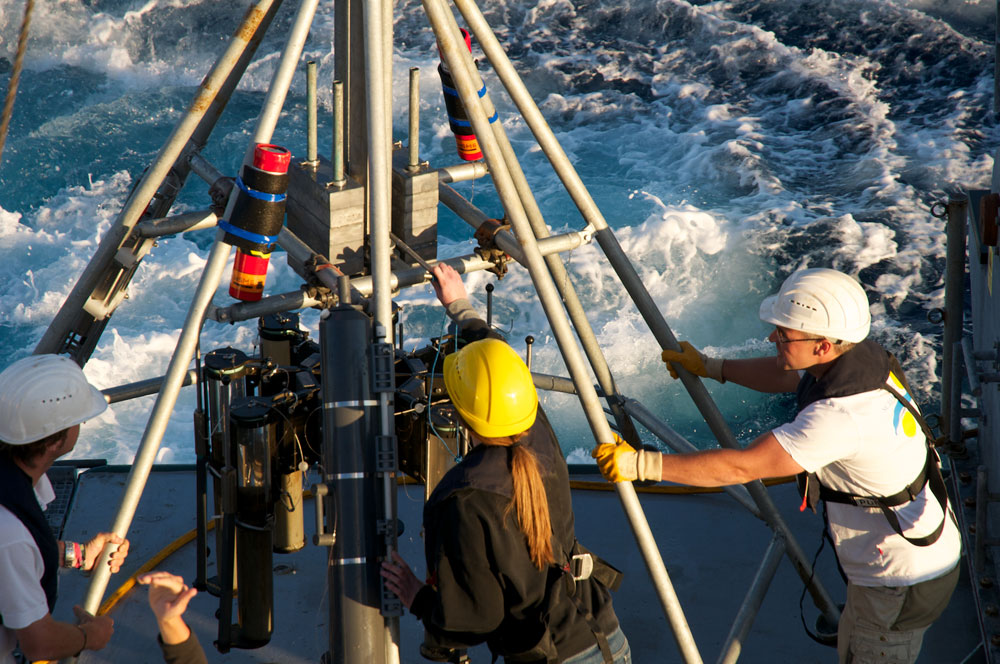 Recovering the multicorer after it collected sediment samples from the seafloor. See the cruise log entry titled Mucking in Mud for an explanation of core subsampling. (Image by Debbie Nail Meyer, Schmidt Ocean Institute)
