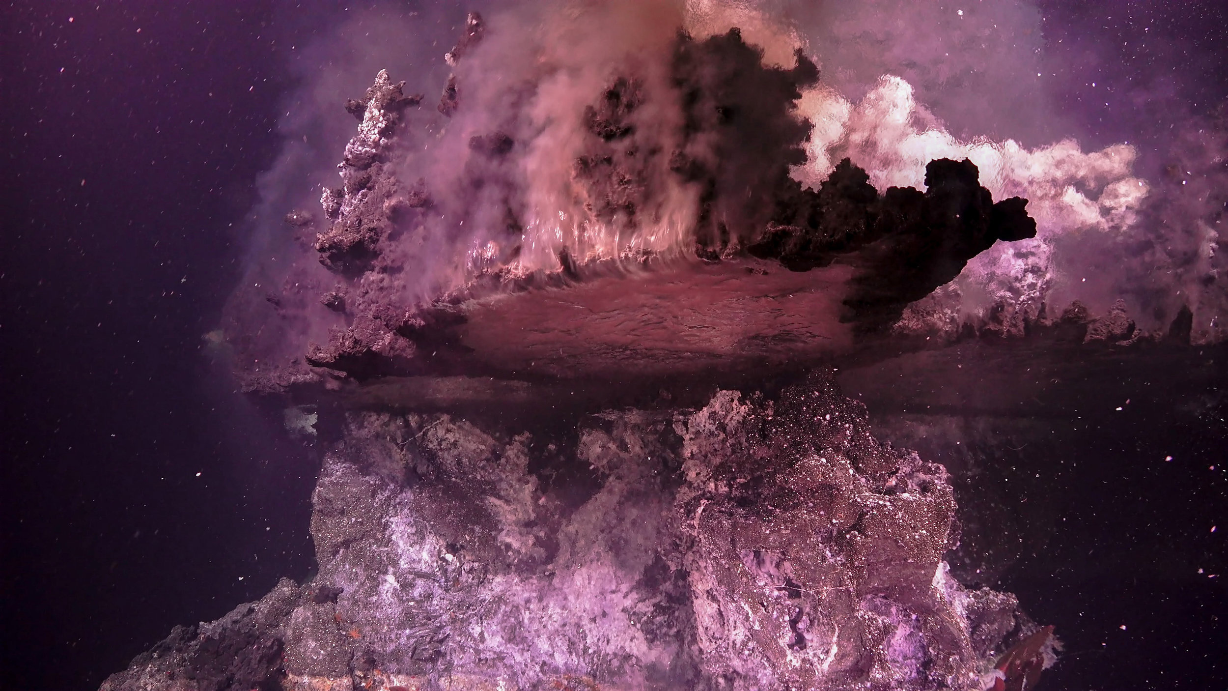 A broken hydrothermal vent flange gushing hot fluid over the side.  (Image courtesy of Schmidt Ocean Institute)