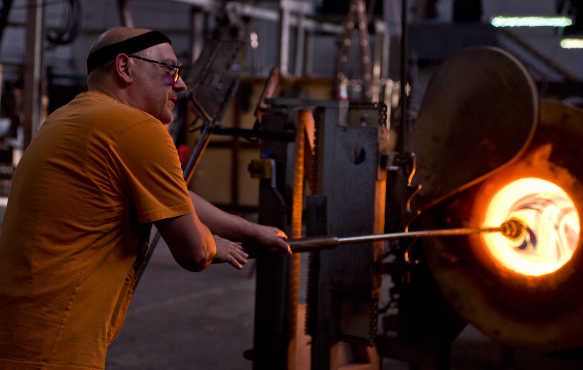 The Master Glass Blower heats the gather to near a molten state.