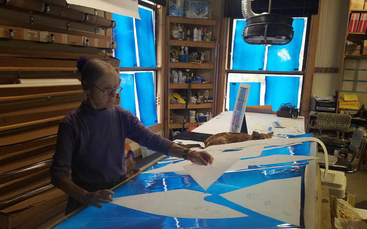 Cindy uses paper patterns to select were to mark the glass.