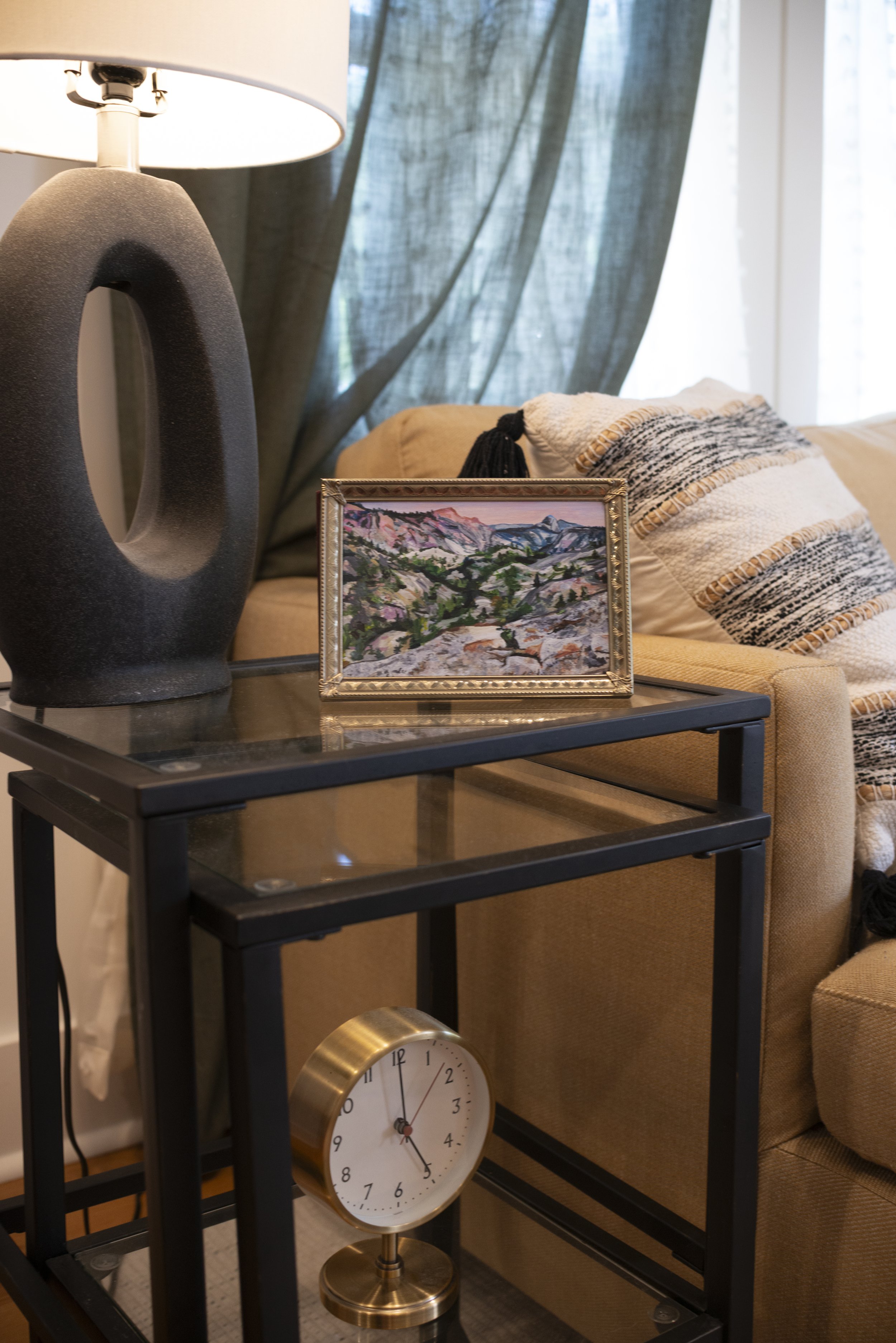 A Yosemite landscape print in a gold frame, displayed on a side table in a living room next to a cozy couch.
