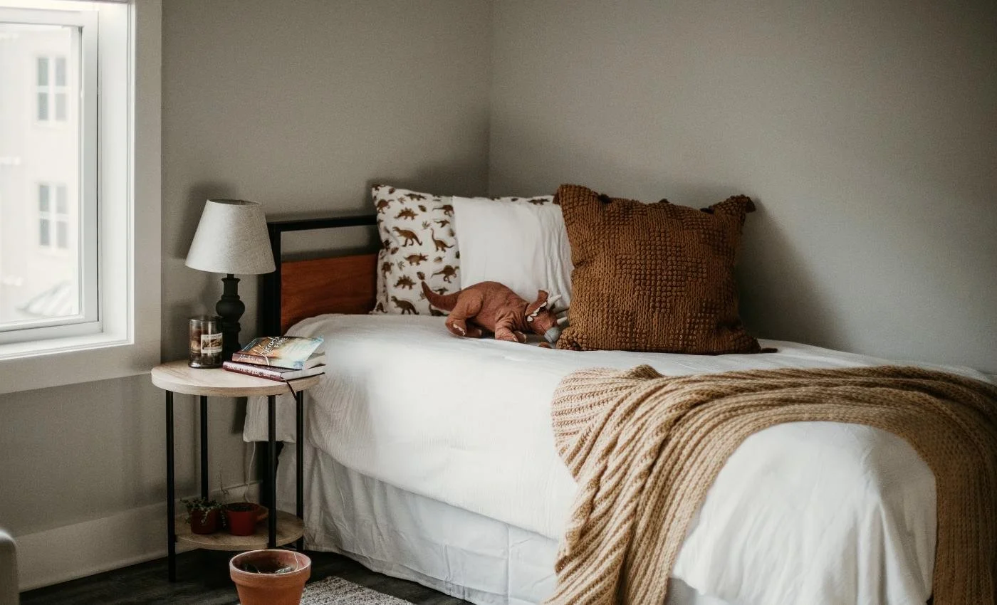 Cozy Airbnb bedroom corner with a knit throw blanket and a small dog toy on the bed
