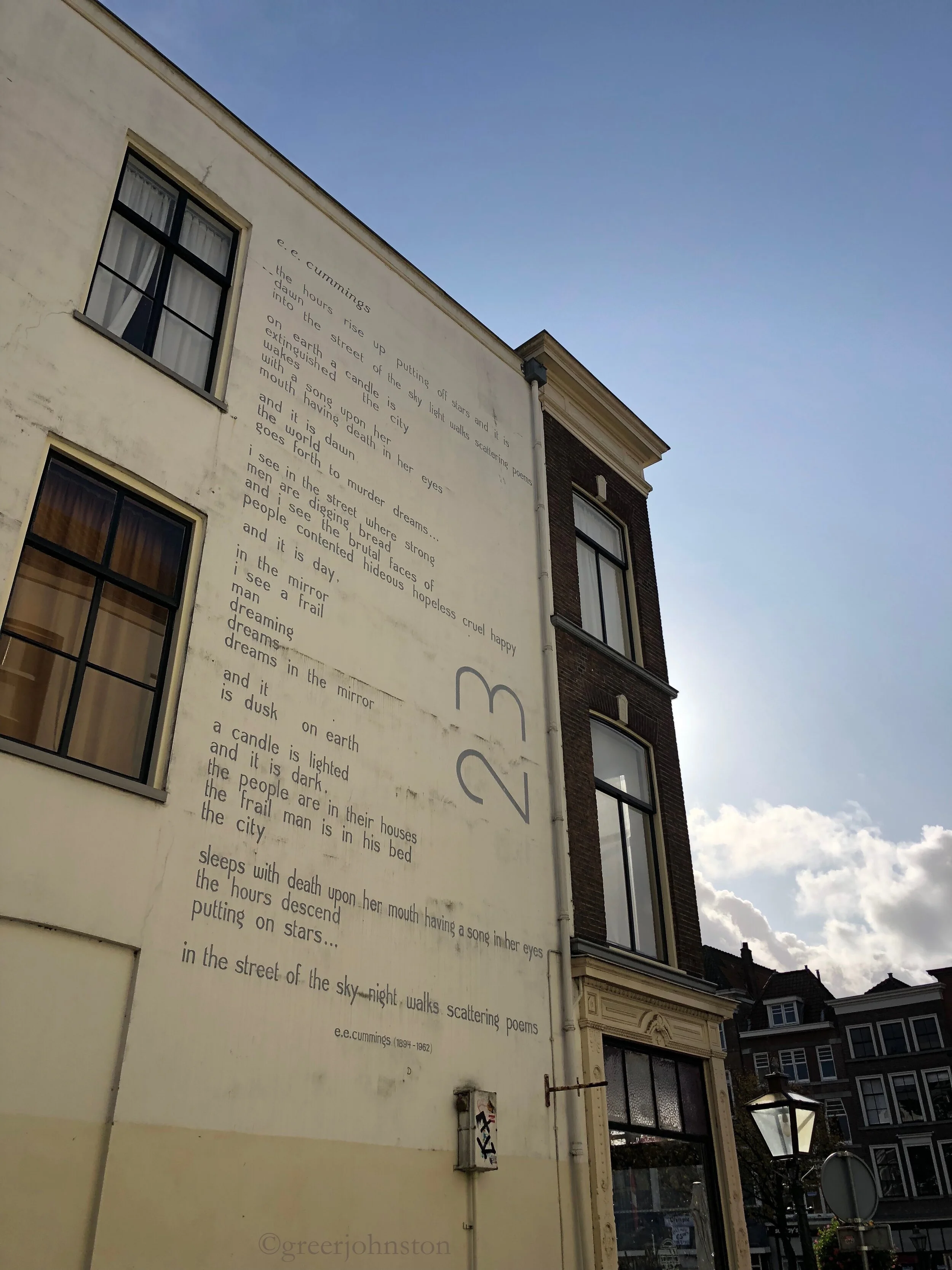 A poem by e e cummings on a wall in Leiden, part of De Muurgedichten Leiden project