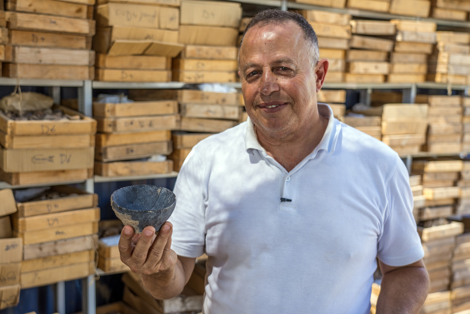 Dr. Hamoudi Khalaily, Antiquities Authority Excavation director, holding a bowl from the Neolithic Period. 