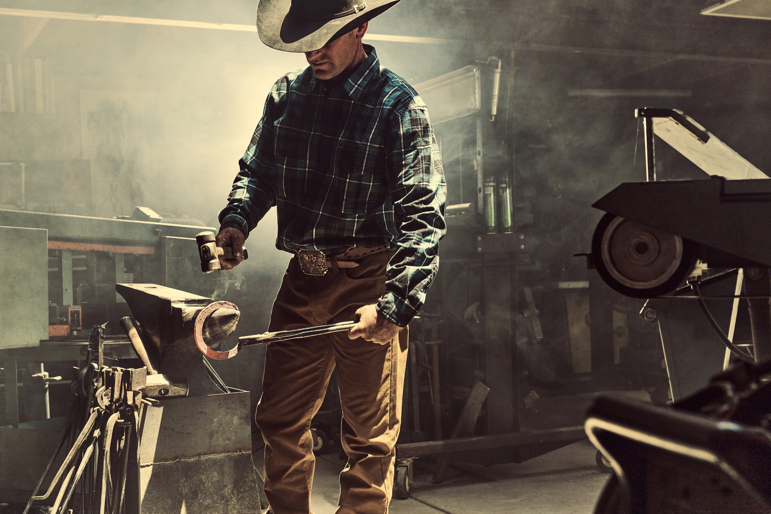 Cowboy striking a hot horseshoe with a hammer