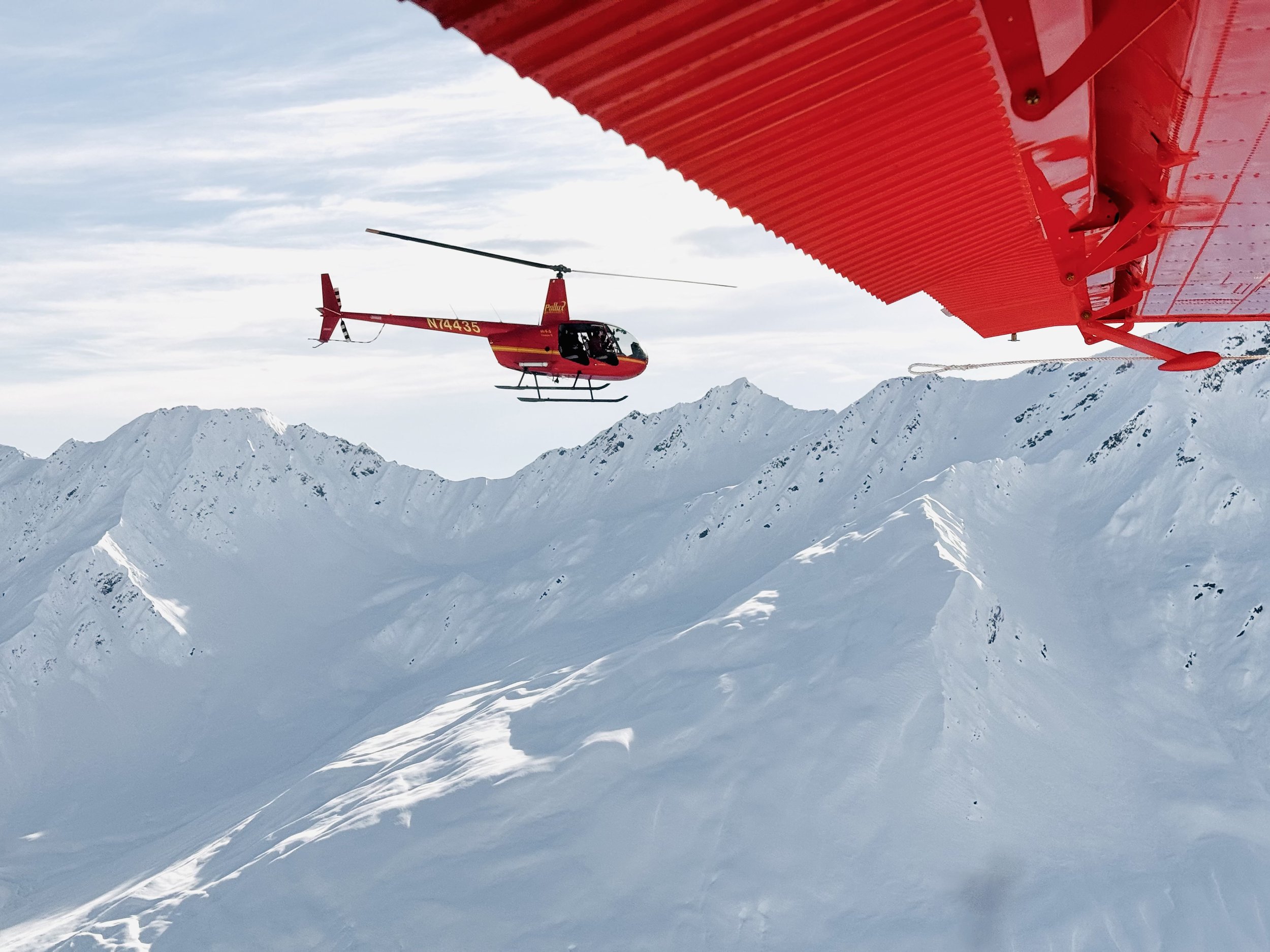 Robinson helicopter above snowy mountains