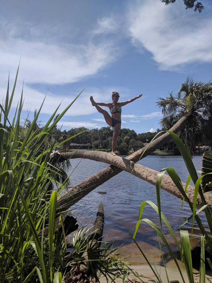 Young woman doing a stretching pose on two crossing palm trees
