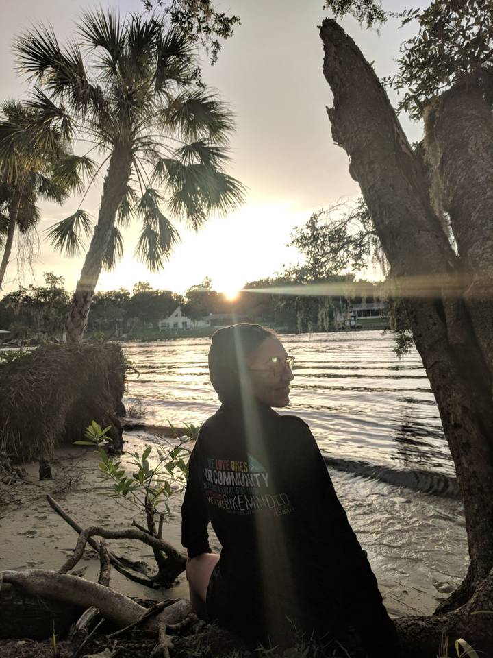 Young woman standing on small beach along the river during sunset