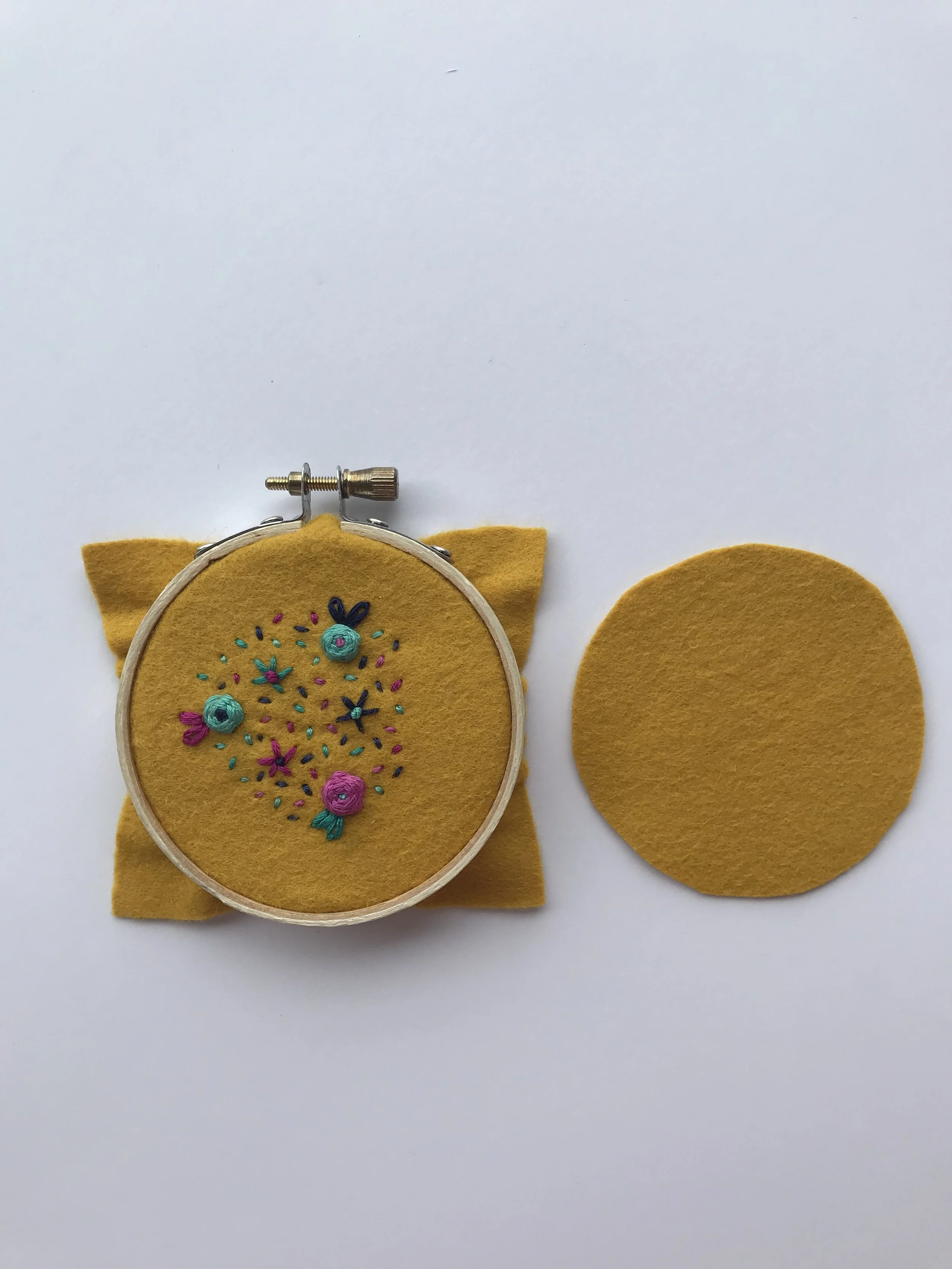 Once your design is complete, remove the embroidered piece of fabric from the hoop. Place the second piece of felt behind the embroidered felt.