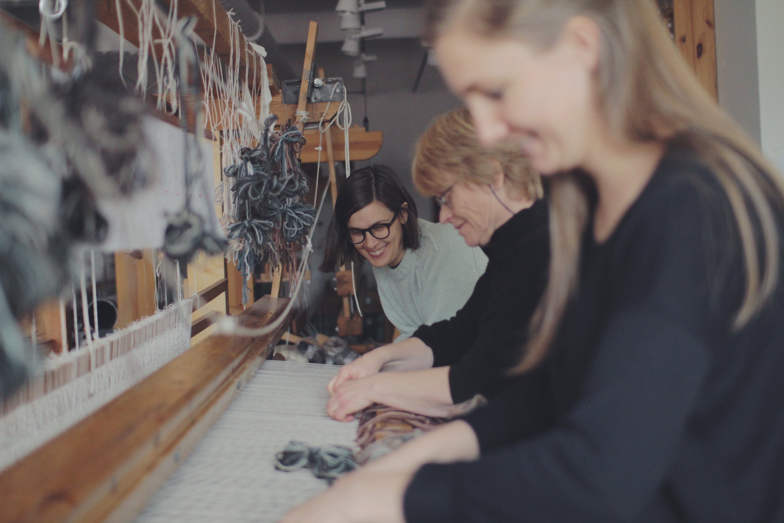  Konstnären Frida Lindberg tillsammans med väverskorna Ebba Bergström och Samantha Gustafsson vid vävstolen. Fotograf: Adam Powers 