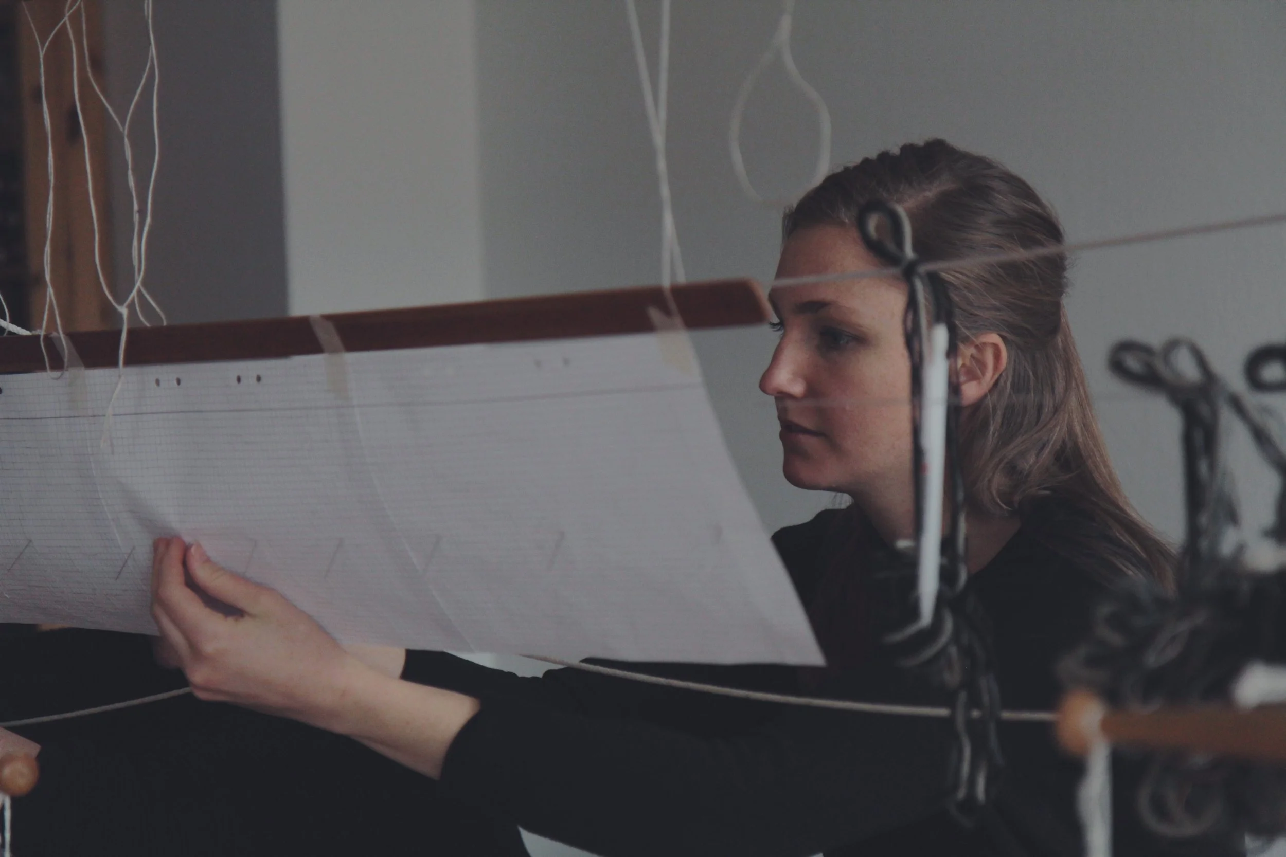  Väverskan Samantha Gustafsson läser av arbetsritningen, mattan vävs i rölakansteknik med ullgarn som inslag och lin i varpen.   Fotograf: Adam Powers 