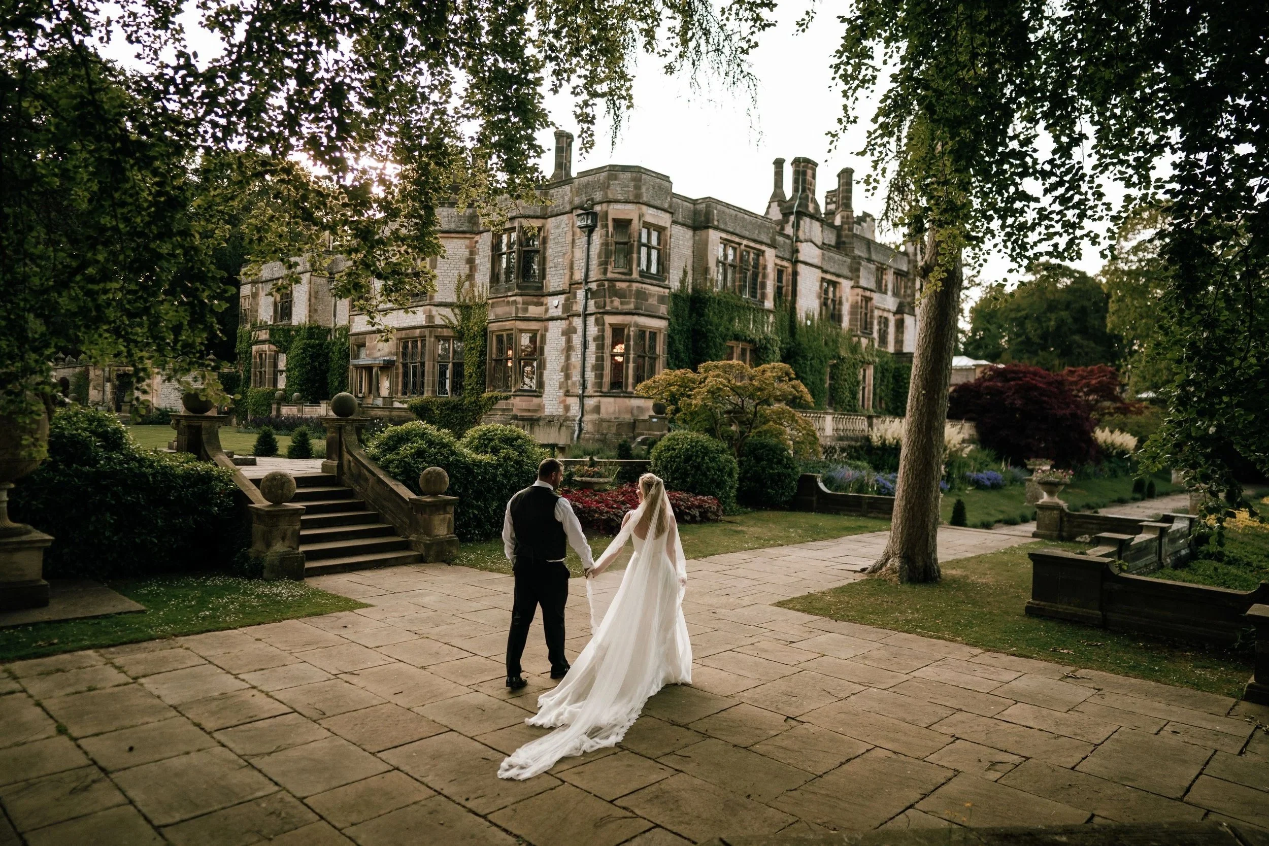 Couple married at thornbridge hall walking through the RHS partner garden in summer, photo by Chris Smith Photography