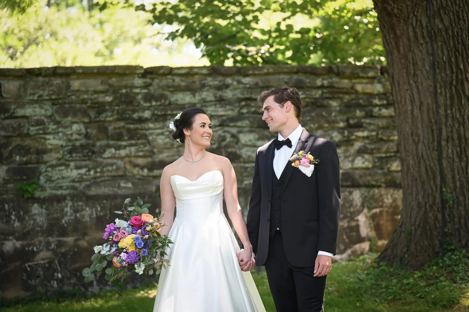 bride and groom under big tree in the formal gardens at Bellevue Hall