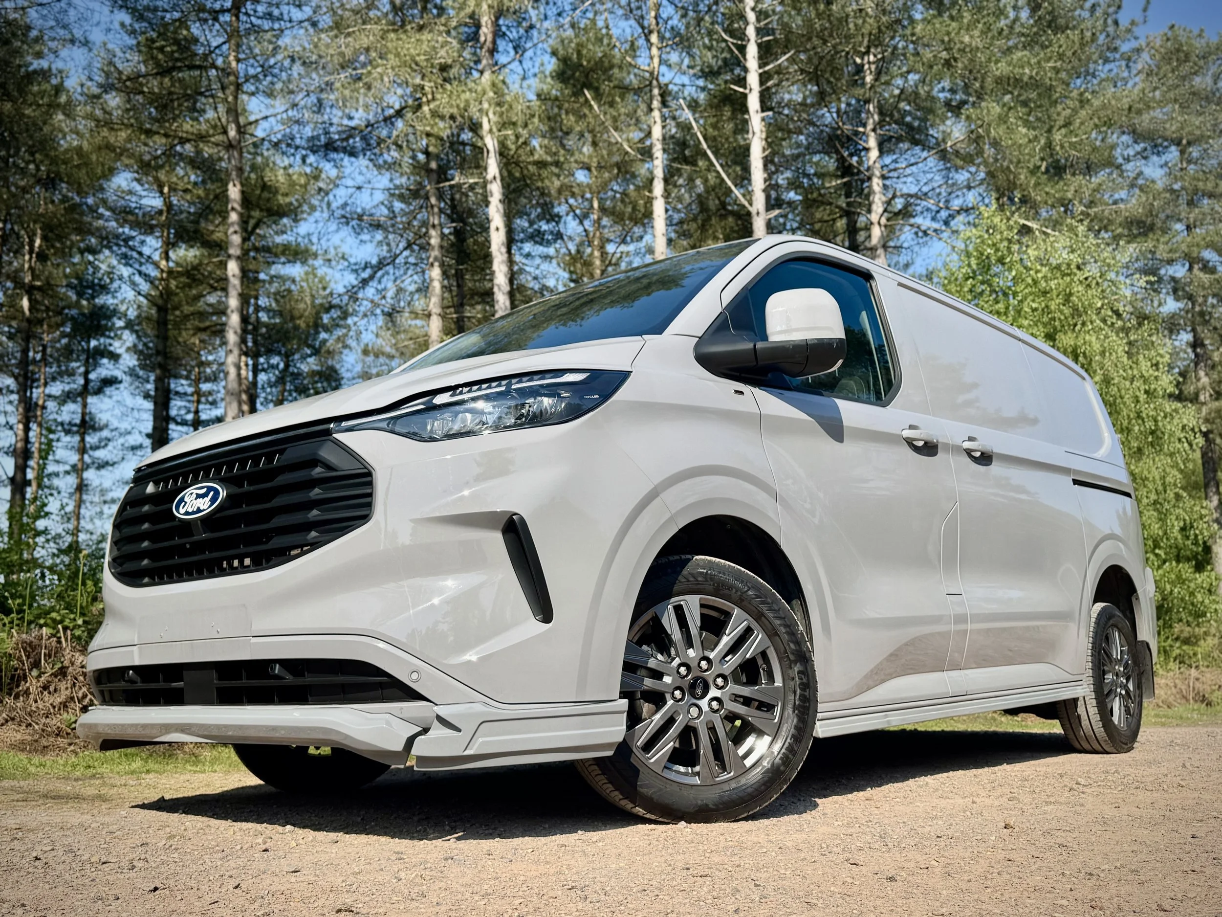 Picture of an SV Sport Van with the SVX kit, the Van is Flat grey with alloy wheels, background is a forest in summer