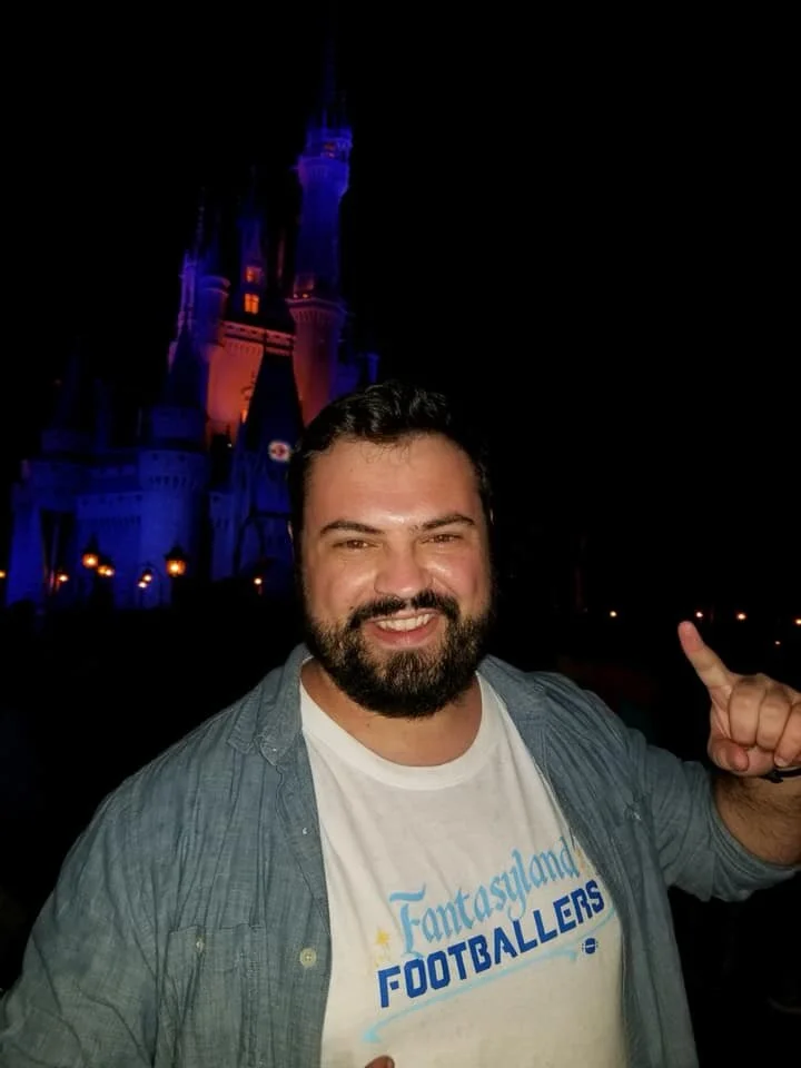 Matt wearing a Fantasyland Footballers shirt while celebrating his fantasy football championship in front of Cinderella Castle at Magic Kingdom