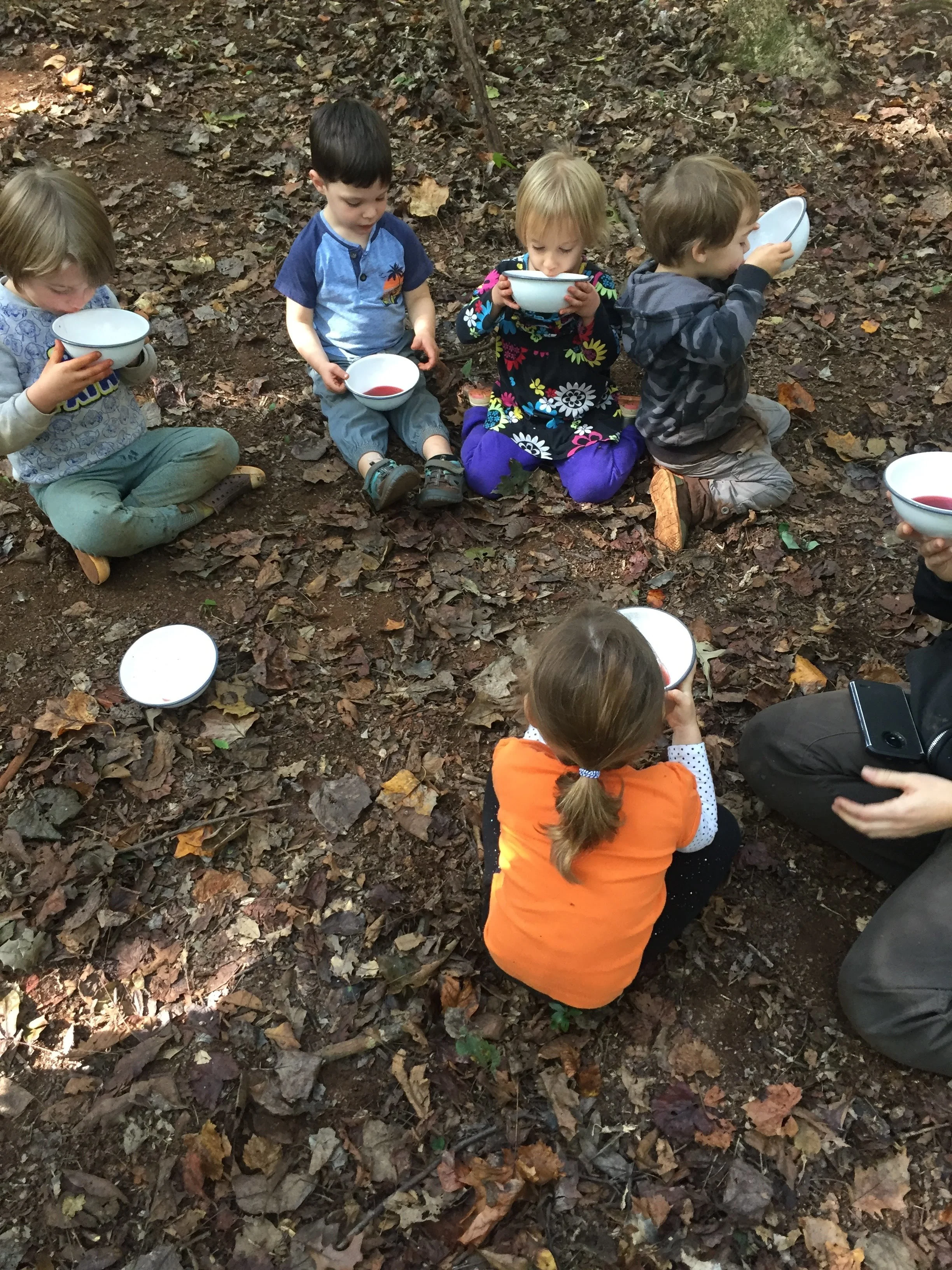 The children enjoying bowls of berry tea to warm up