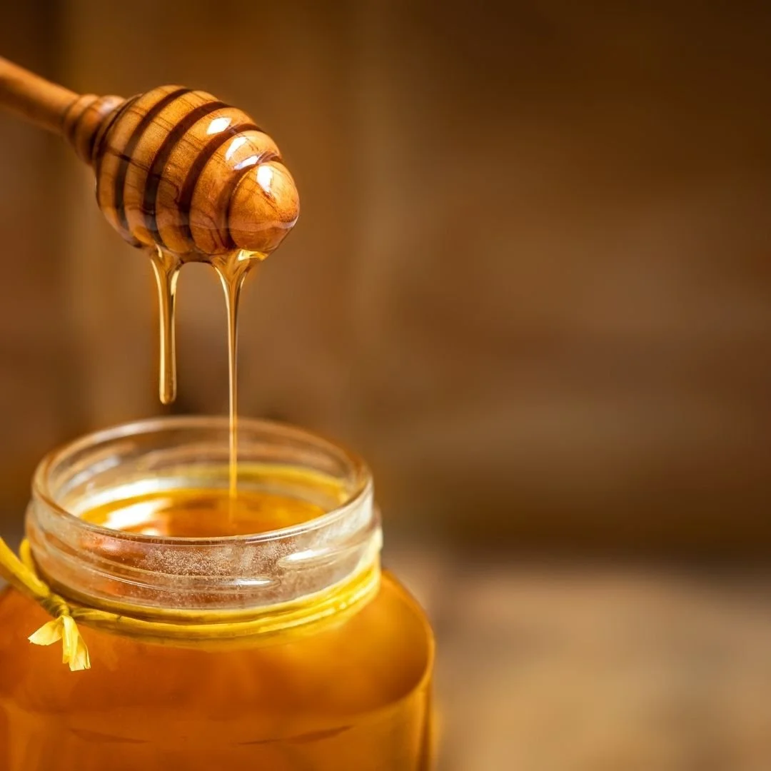 Honey dripping from a wooden dipper to make a spicy hot honey butter glaze for pork chops.