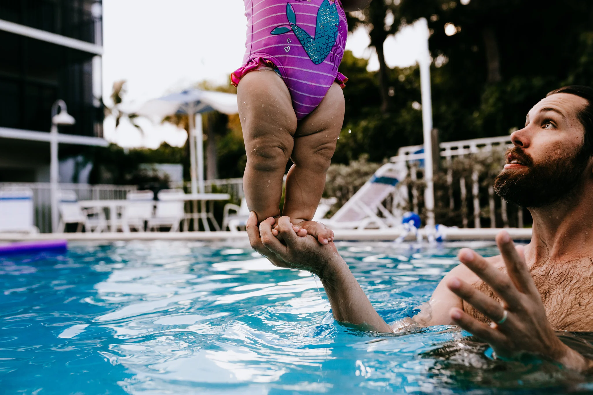 dad balances baby on palm in family beach photo