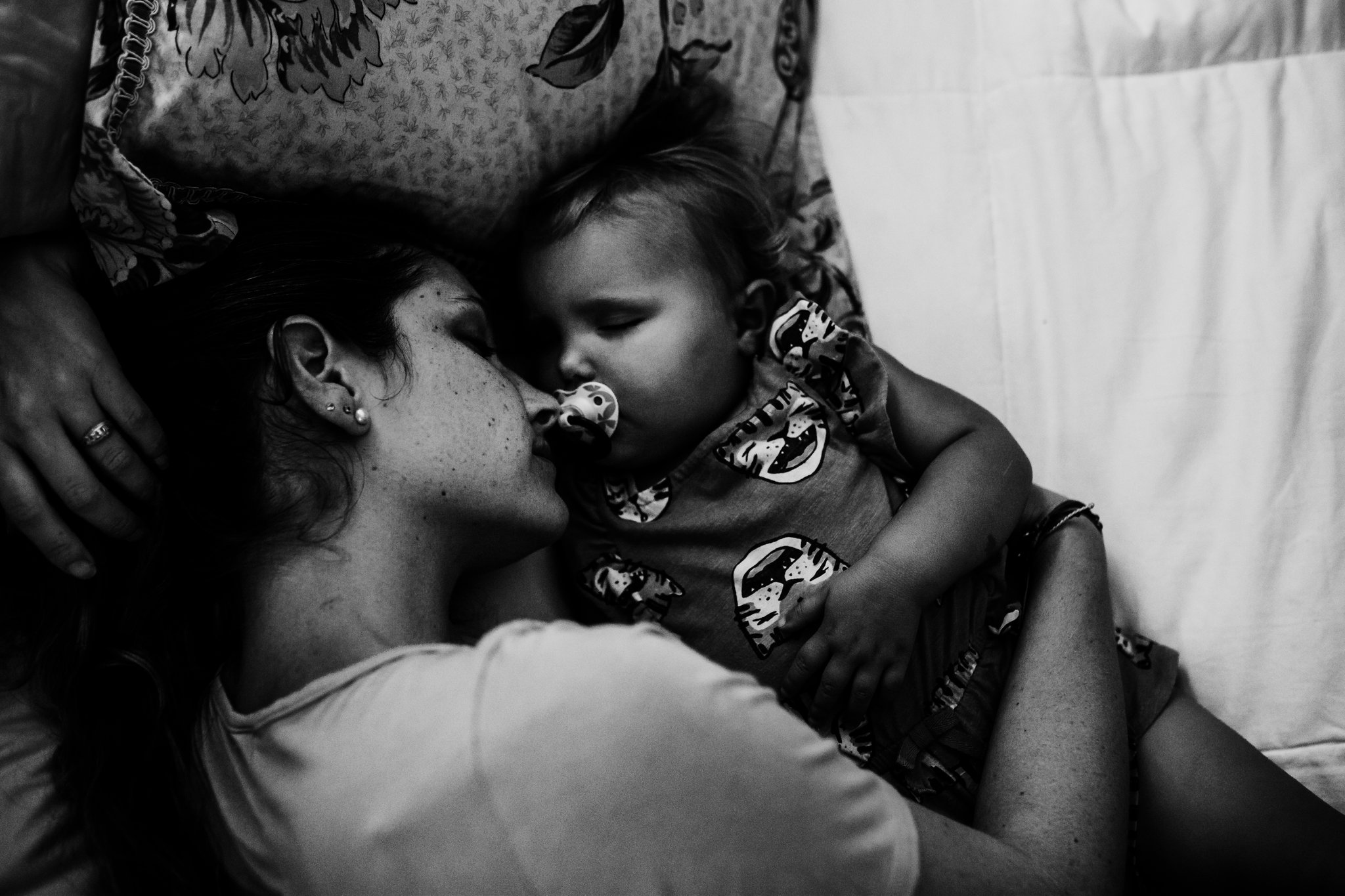 Mother cuddles baby daughter in bed 