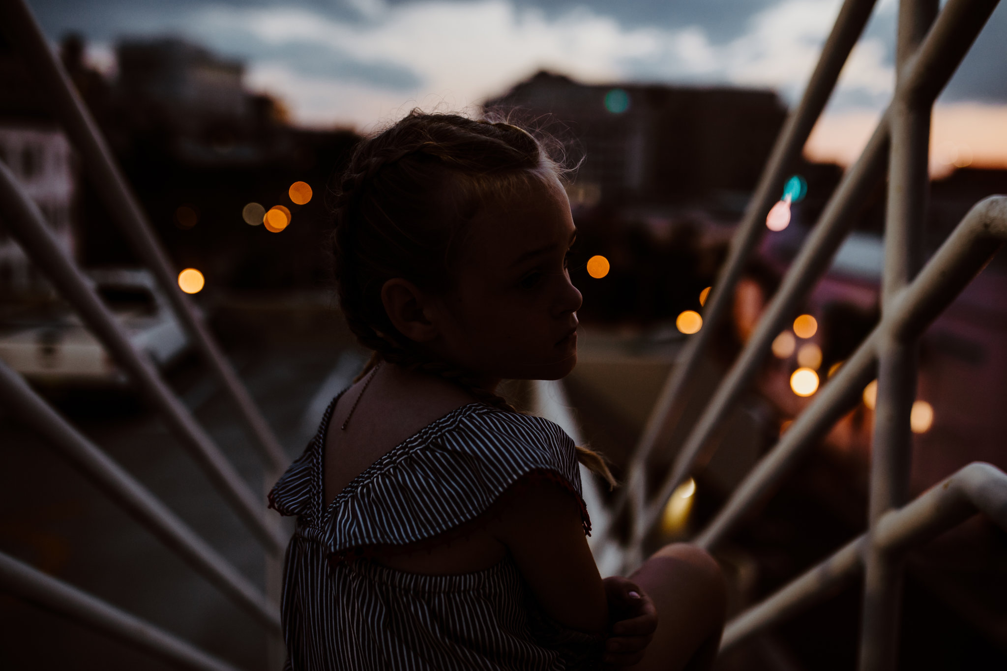 Little girl sits on stairs with downtown Fort Myers lights in background