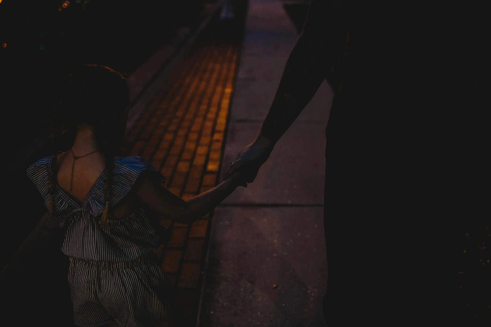 Mother and daughter hold hands walking down street in downtown fort myers 