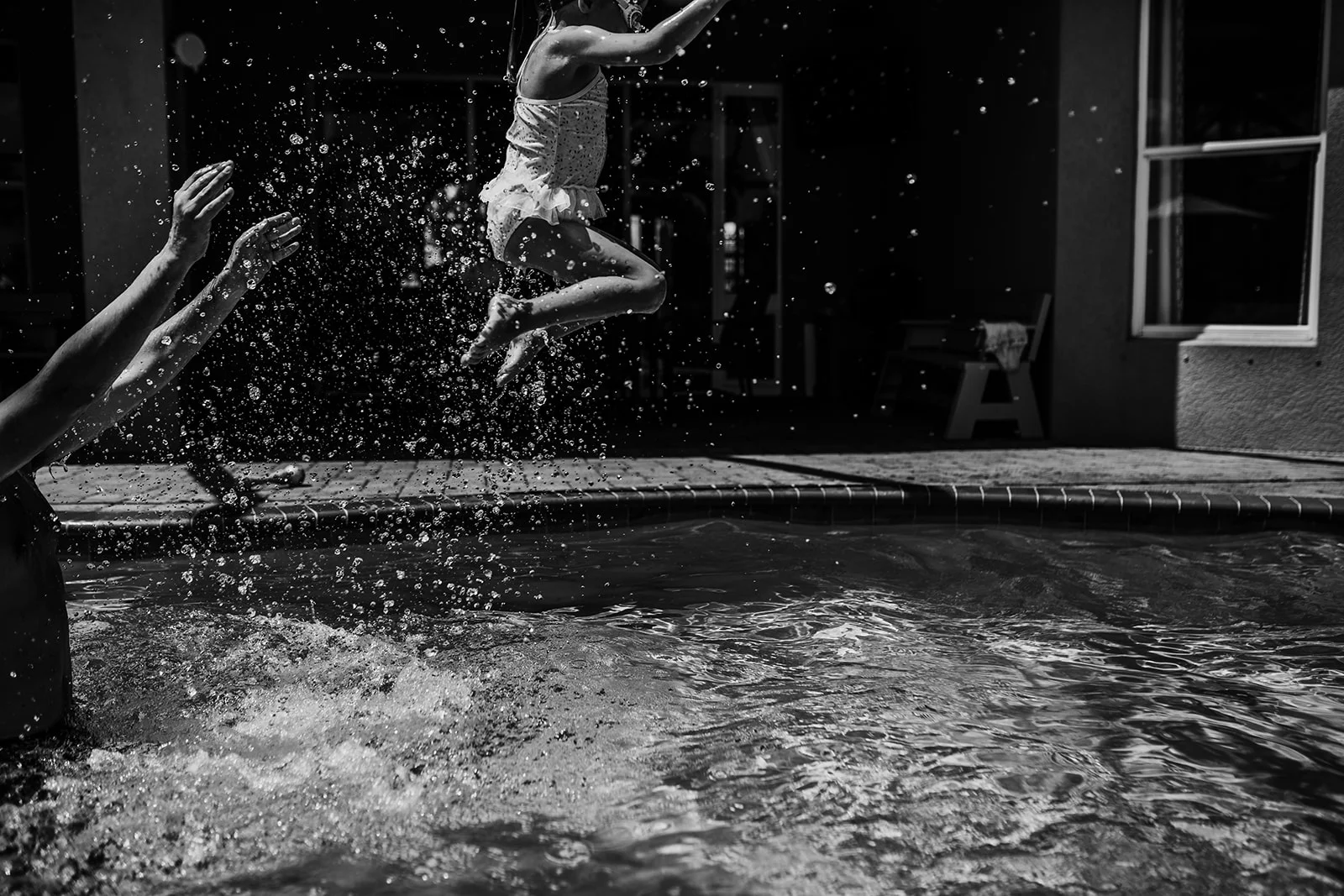 dad throws daughter in the air in the pool