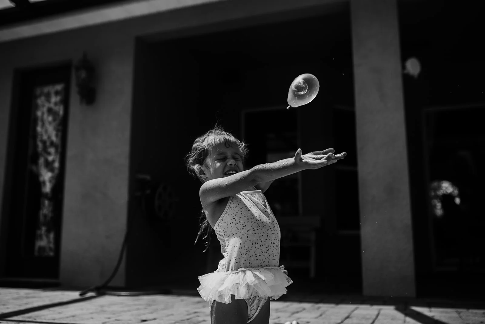 Little girl reaches her arms out to catch water balloon thrown at her