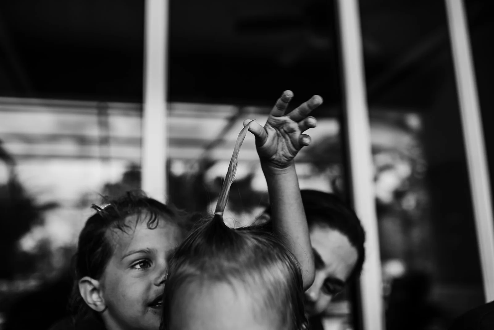 sister pulls toddler's hair to make it stand up straight